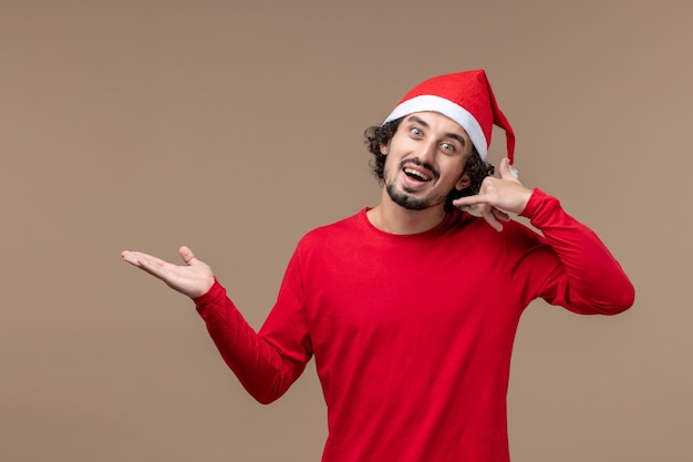 Front view young man with excited expression on the brown background holiday emotion christmas