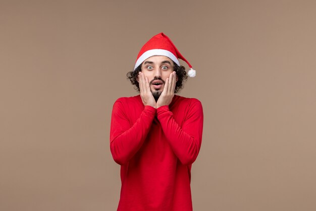 茶色の机の上の興奮した顔を持つ正面図の若い男クリスマス感情休日