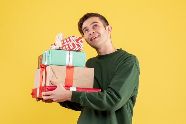 Front view young man with green sweater looking at high standing on yellow 