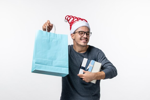 Front view of young man with holiday gifts on white wall