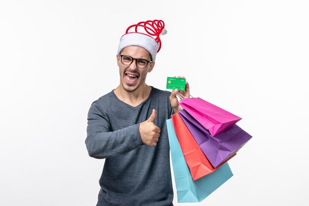 Front view of young man with holiday packages on a white wall