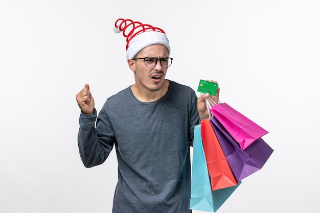 Front view of young man with holiday packages on white wall