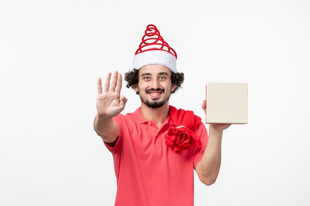 Front view of young man with holiday present on a white wall