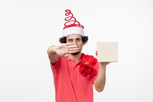 Front view of young man with holiday present on the white wall