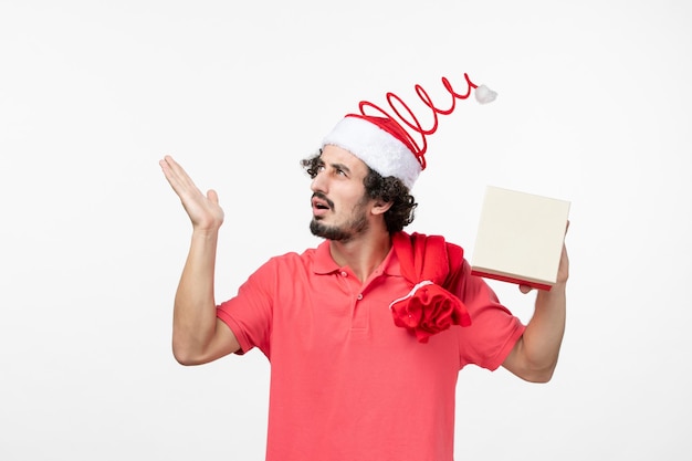 Vista frontale del giovane con regalo di festa sul muro bianco