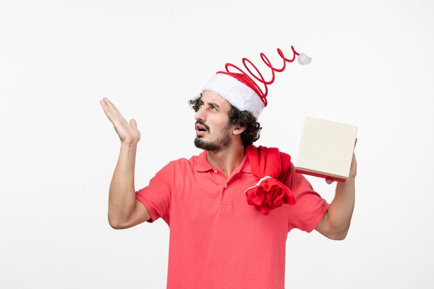 Front view of young man with holiday present on the white wall