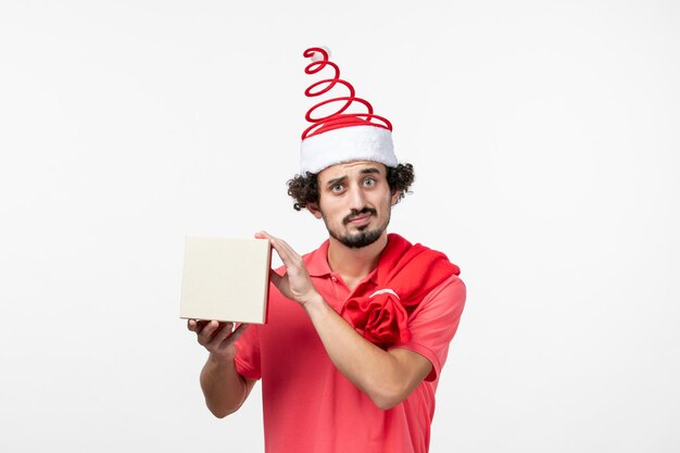 Front view of young man with holiday present on white wall