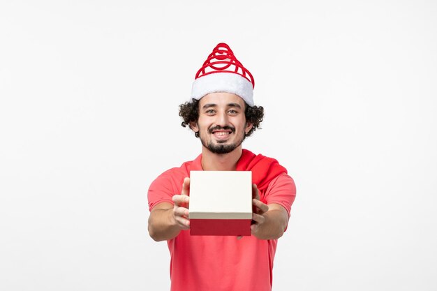Front view of young man with holiday present on white wall