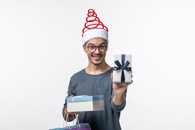 Front view of young man with holiday presents on a white wall