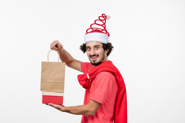 Front view of young man with holiday presents on white wall