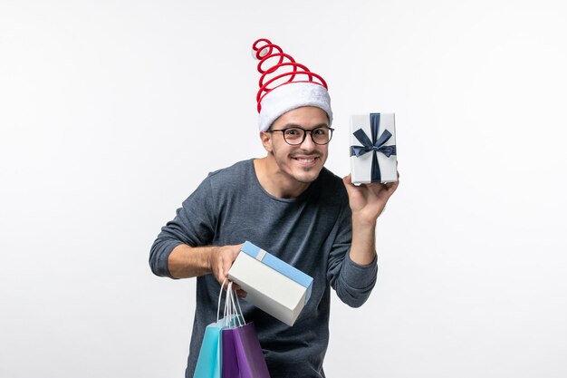 Front view of young man with holiday presents on white wall