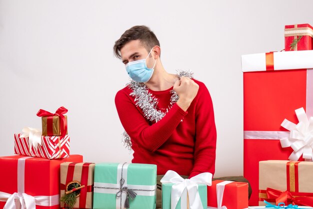 Front view young man with mask showing strength sitting around xmas gifts