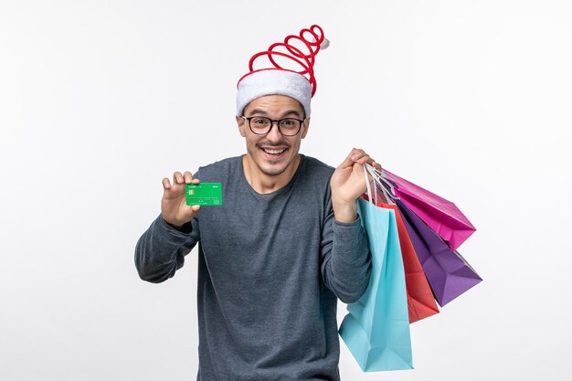 Front view of young man with packages and bank card on white wall