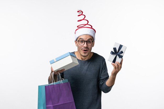 Front view of young man with packages and presents on white wall