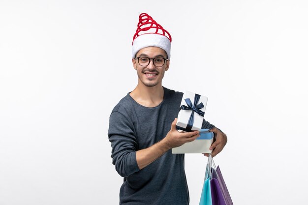 Front view of young man with packages on the white wall