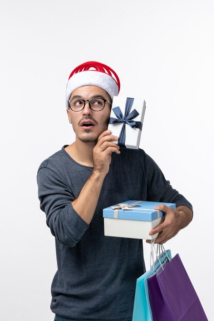 Front view of young man with packages on white wall