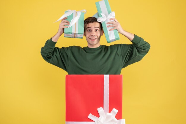 파티 모자와 노란색 배경에 큰 giftbox 뒤에 서 선물 전면보기 젊은 남자
