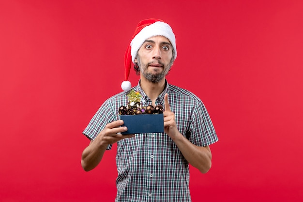 Front view young man with plastic toys on red background