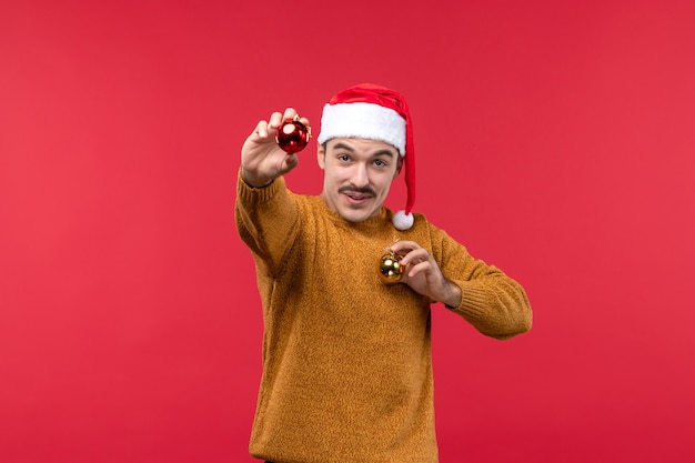 Free photo front view of young man with plastic toys on red wall