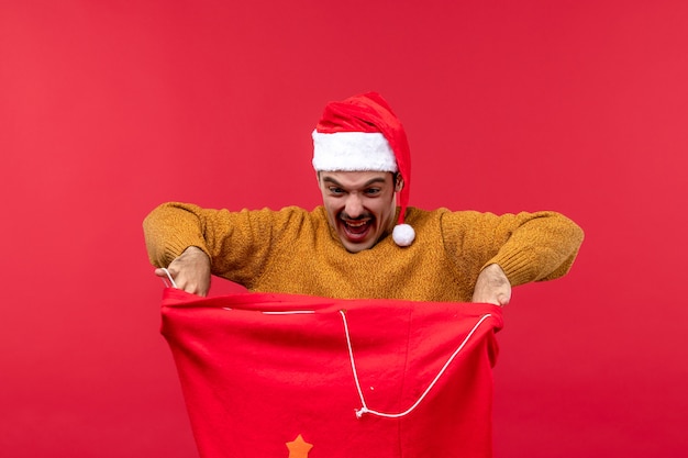 Free photo front view of young man with present bag on a red wall