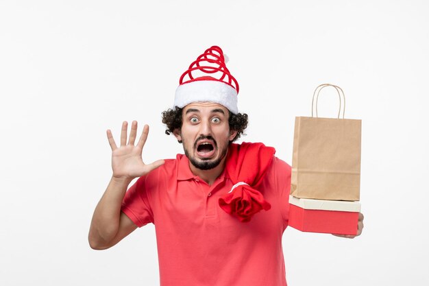 Front view of young man with presents on a white wall