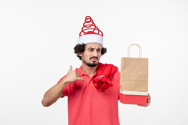 Front view of young man with presents on white wall