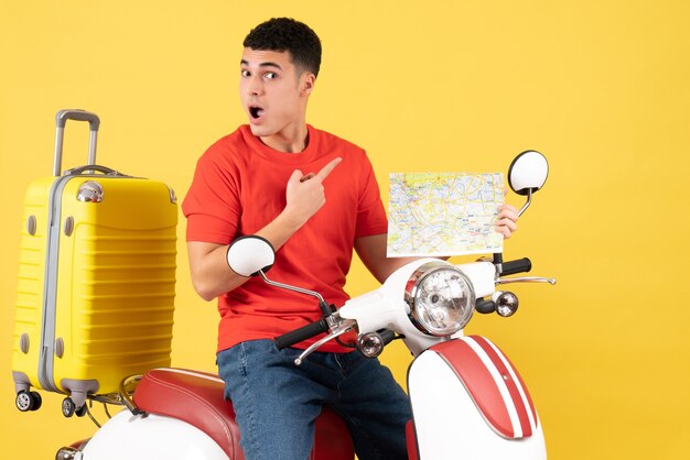 Front view young man with prying eyes on moped holding travel map