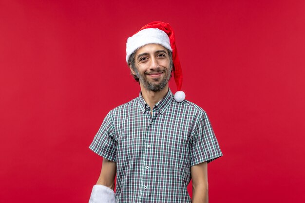 Front view of young man with red christmas cap on red wall