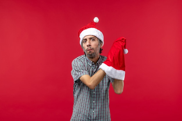 Front view of young man with red christmas cap on the red wall