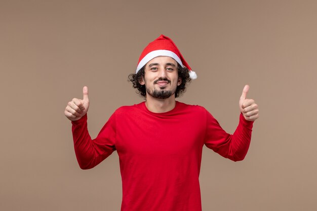 Front view young man with red christmas cape on a brown background christmas emotion holiday