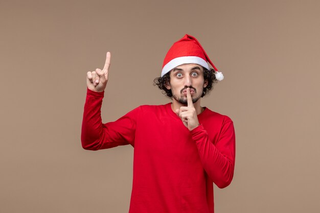 茶色の背景の休日の感情のクリスマスに赤いクリスマスマントと正面図の若い男