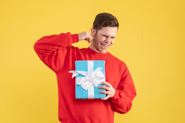 Front view young man with red sweater closing his eyes on yellow background