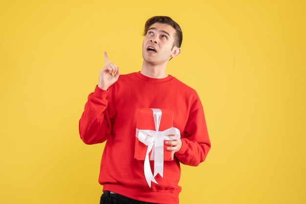 Free photo front view young man with red sweater looking up on yellow background