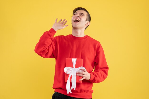 Front view young man with red sweater looking up on yellow background