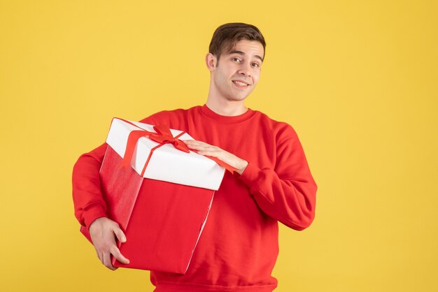 Front view young man with red sweater standing on yellow background copy place