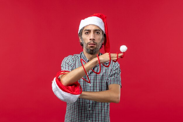 Front view of young man with red toy cap on red wall