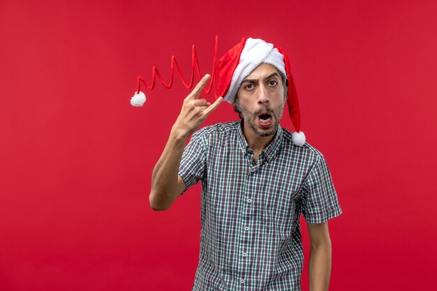 Front view of young man with rocker pose on red wall