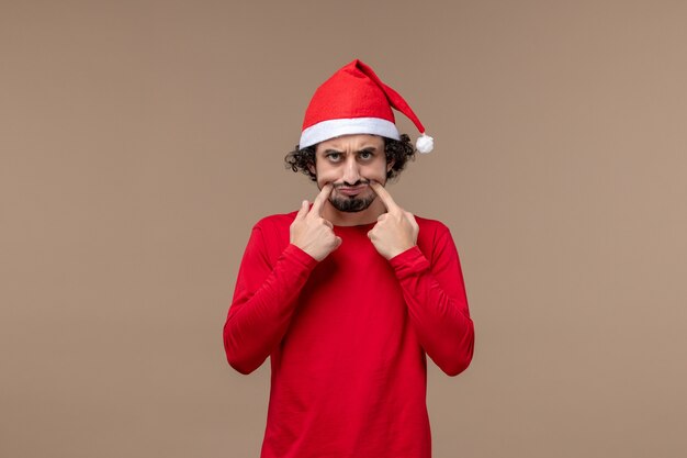 Вид спереди молодой человек с грустным лицом на коричневом фоне рождественские эмоции праздник