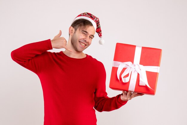 Front view young man with santa hat making call me phone gesture on white background