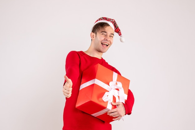 Front view young man with santa hat making thumb up sign on white background