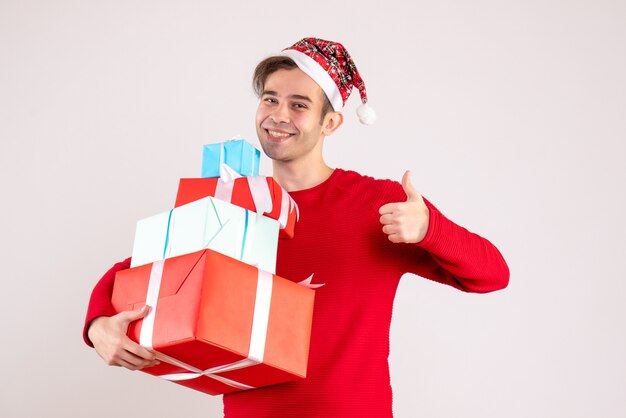 Front view young man with santa hat making thumb up sign on white background