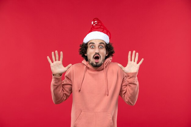 Front view of young man with shocked expression on red wall
