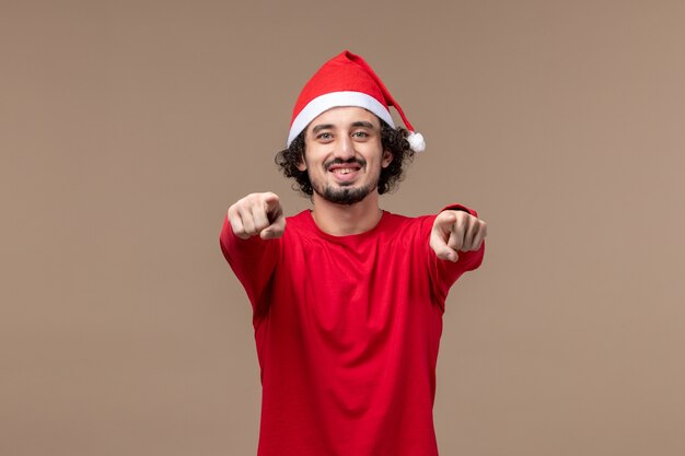 Вид спереди молодой человек с улыбающимся лицом на коричневом фоне праздничные эмоции рождество