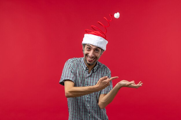 Front view of young man with smiling face on red wall