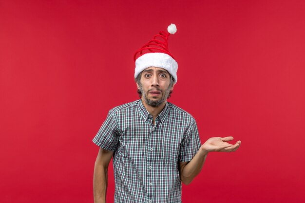 Front view of young man with sorry expression on red wall