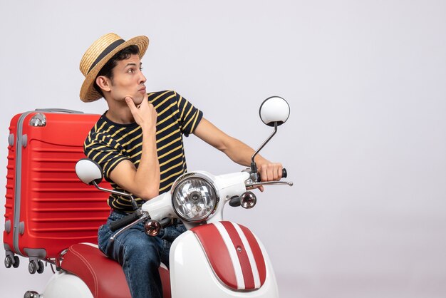 Front view young man with straw hat on moped looking at right