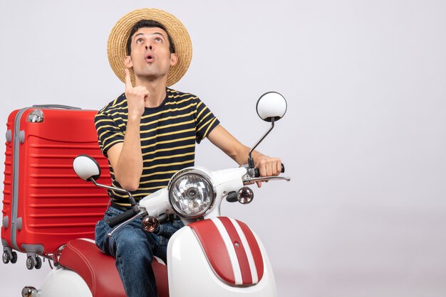 Front view young man with straw hat on moped pointing finger up
