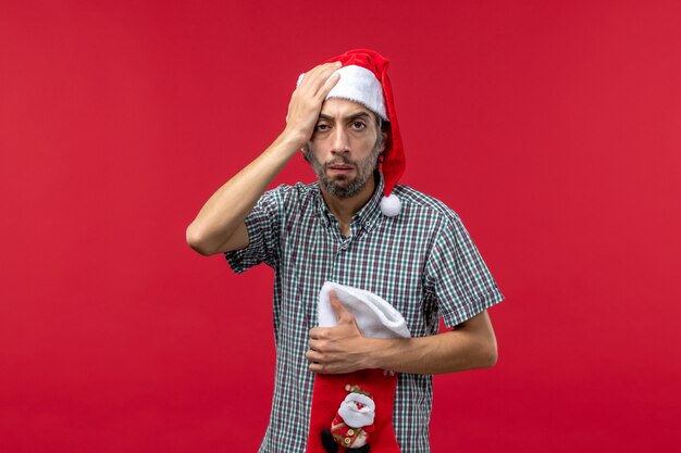 Front view of young man with stressed expression on red wall