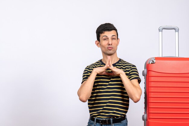 Front view young man with striped t-shirt and suitcase joining hands