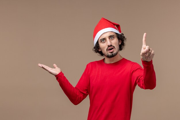 Front view young man with surprised expression on brown background holiday emotions christmas